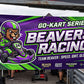 Custom 3x6 racing team vinyl banner hung on a 10x10 canopy tent at the track, printed by Beaver Slaps